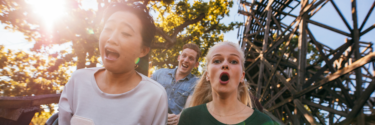 Can Thrill-Seeking Be a Symptom of Depression? Friends on a roller coaster. Woman of color.