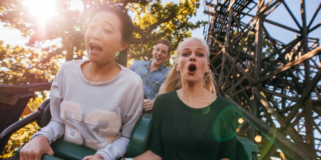 Can Thrill-Seeking Be a Symptom of Depression? Friends on a roller coaster. Woman of color.