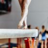 Woman gymnast exercises on balance beam.