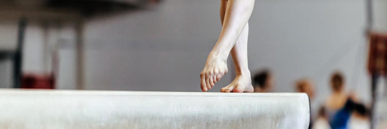 Gymnastics Changed the Way I View My Disability Woman gymnast exercises on balance beam.