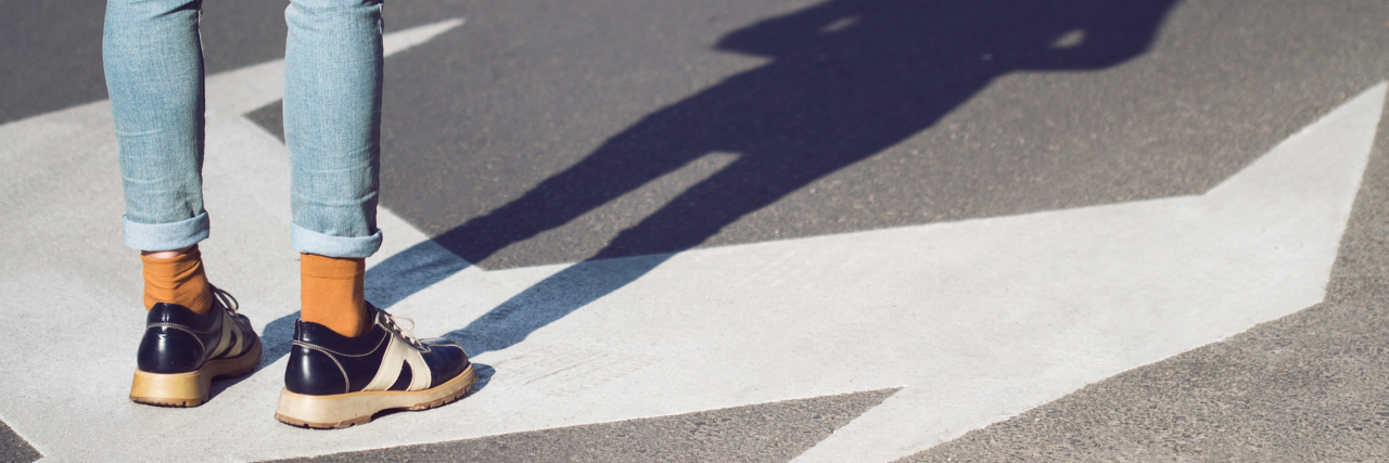 Making Choices With Myalgic Encephalomyelitis woman standing on an arrow in the street that points in two opposite directions