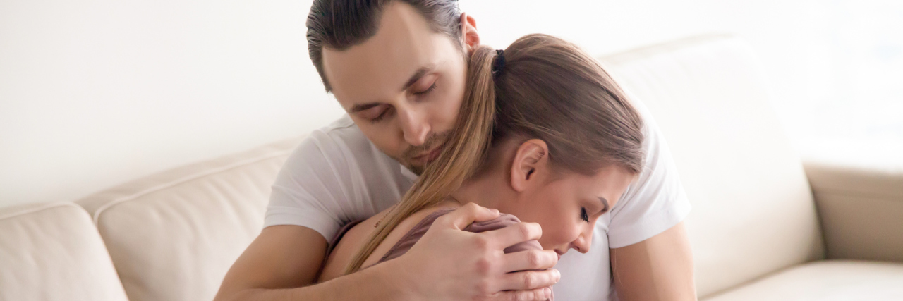 What to Know About Relationships With Someone With PTSD couple embracing on couch sad or upset