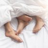 Couple's feet sticking out from under covers.