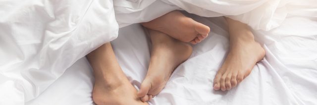 a couple's feet sticking out from under the sheets