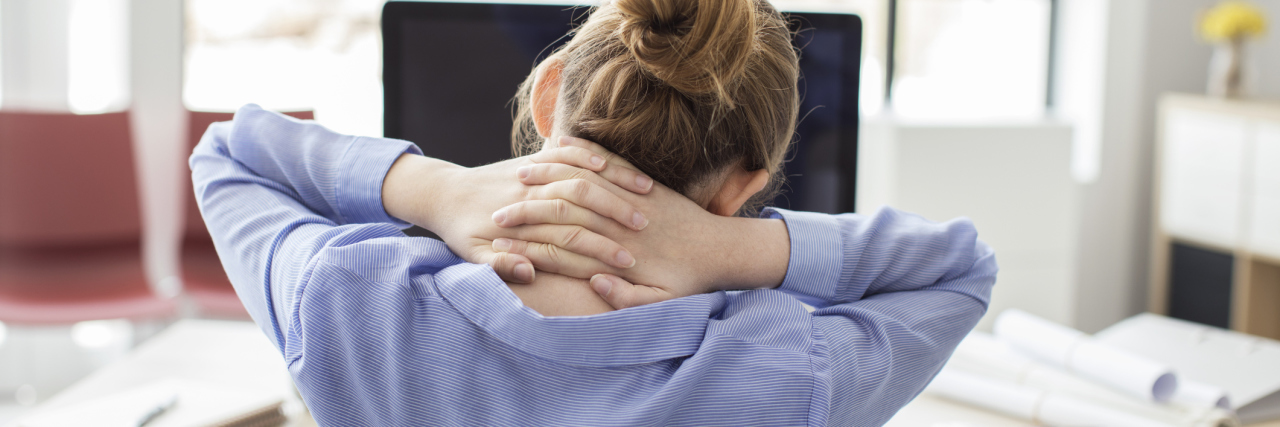 woman in office tired or stressed with hands behind neck