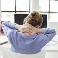 woman in office tired or stressed with hands behind neck