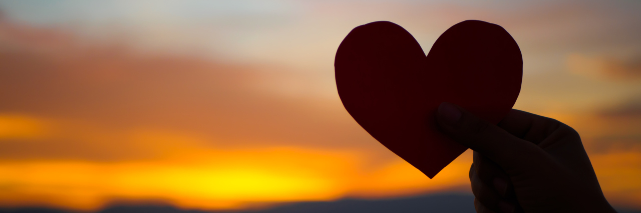 Thank You to My Parents for Supporting Me Through Lyme Disease silhouette of a hand holding a cut-out heart against a sunset