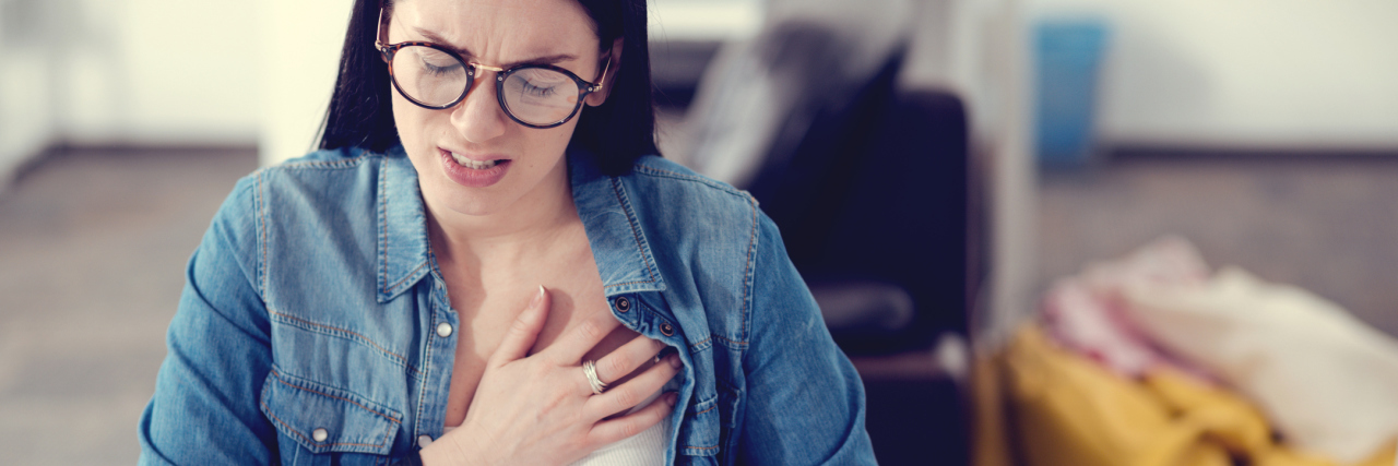 woman sitting at a desk and clutching her chest in pain
