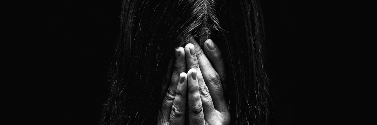 black and white photo of woman covering face with hands