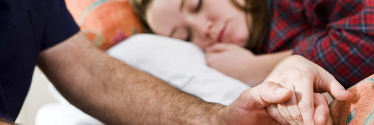 Dear Caregivers, I Took You for Granted A man holding a girl's hand, who is laying in bed.