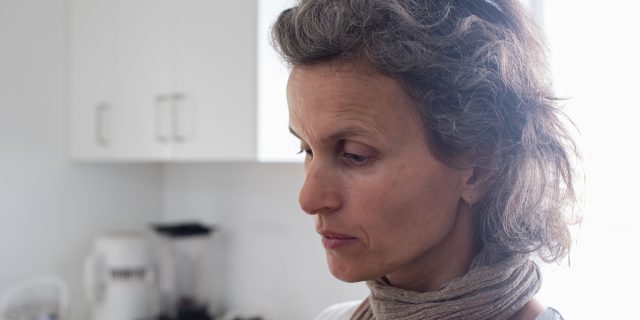 A woman in her kitchen, staring off into space.