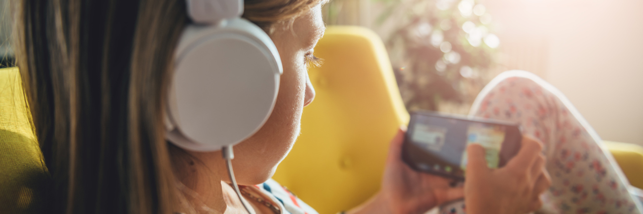 What I Wanted to Tell the Girl in the Waiting Room at the Heart Clinic A young girl on a phone, wearing headphones.