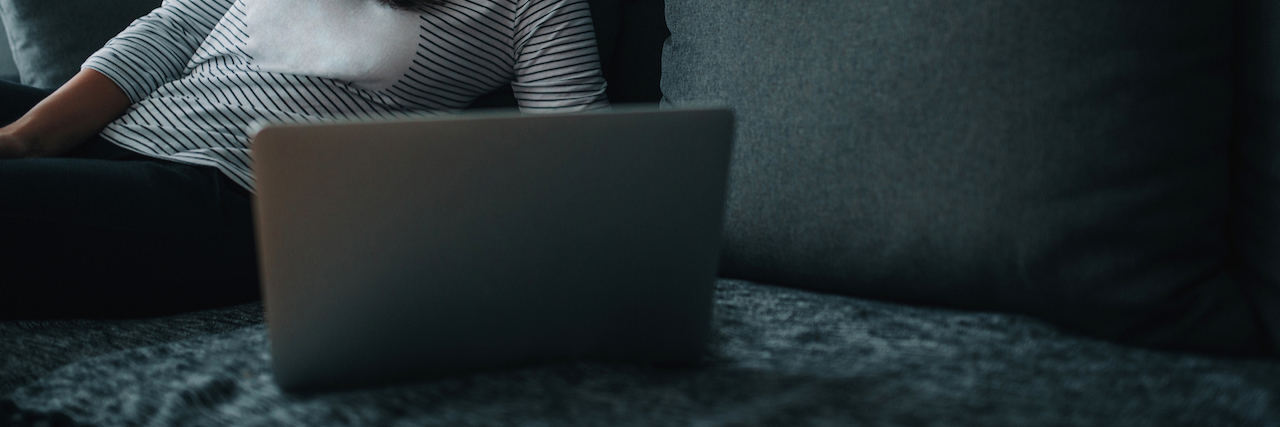 Reasons to Share About Your Chronic Illness on Social Media Woman sitting on her bed looking at a computer