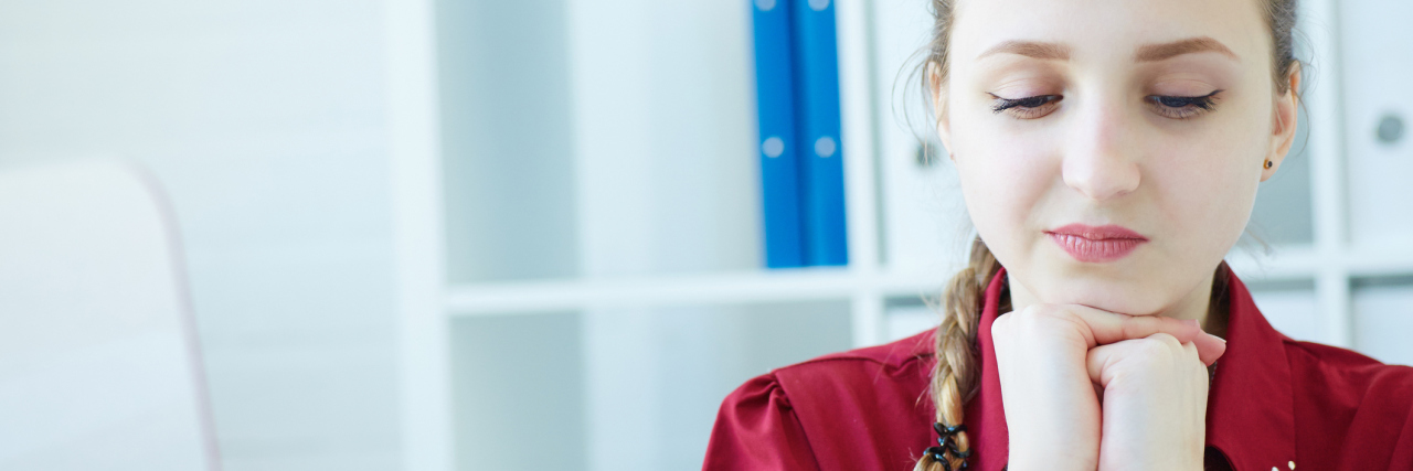 The ‘Trivial’ Activity That Helped Me Beat My Anxiety pensive young woman smiling while looking down at something on table