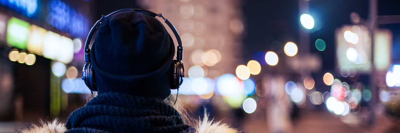 Woman wearing headphones walking at night.