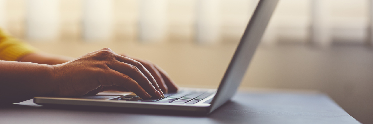 Experiencing Grief as the Parent of a Child With a GRIN2B Mutation Woman typing on laptop in the office, toned image