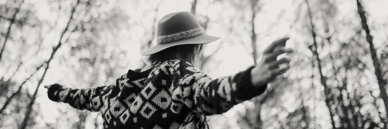 Removing Toxic People From My Life After Chronic Illness black and white photo of a woman wearing a sweater and a hat while walking in the forest