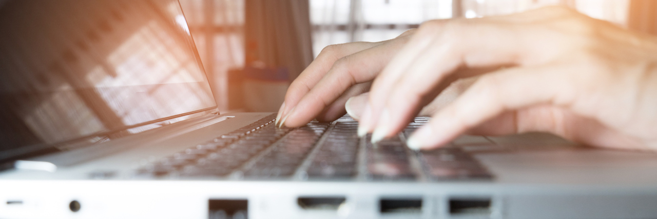 Why I Write About My Endometriosis Woman's hands typing on a computer.