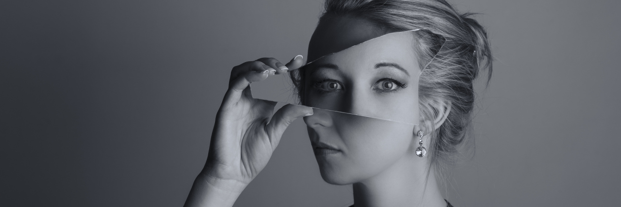 A picture of a woman holding a mirror to her face, showing her eyes at a unique angle.