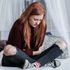 redhead young woman sitting on bed depression pain