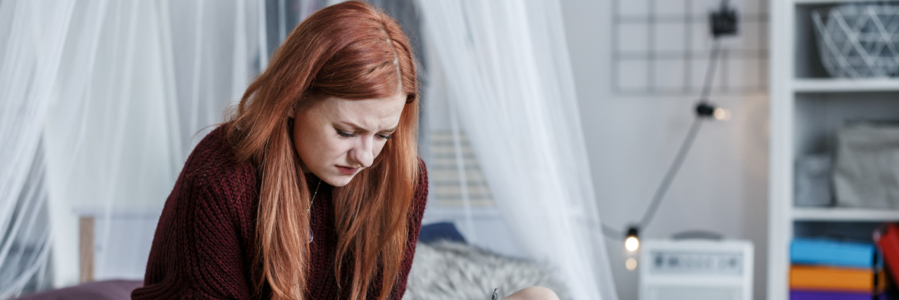 redhead young woman sitting on bed depression pain