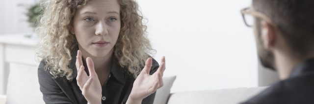 young woman talking to male therapist while gesturing with hands