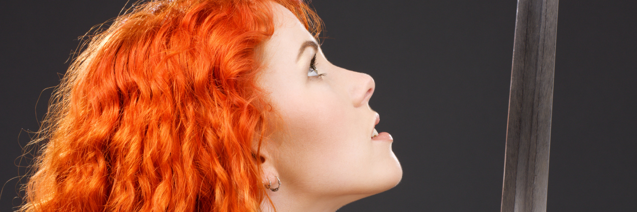 Why Telling Me I 'Don't Look Sick' Is a Double-Edged Sword A red headed woman looking at a sword.