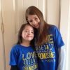 Two sisters hugging. One with Down syndrome. They are weraing blue shirts that say, "Love doesn't count chromosomes"