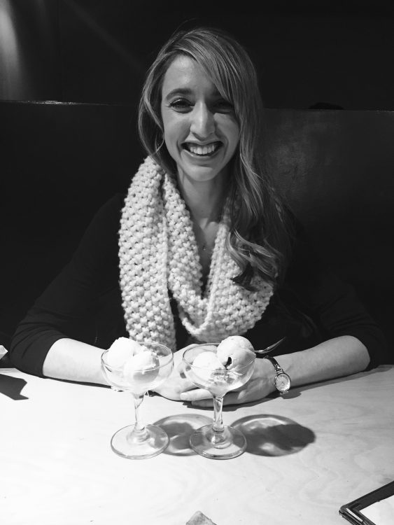 black and white photo of a woman sitting at a table and smiling