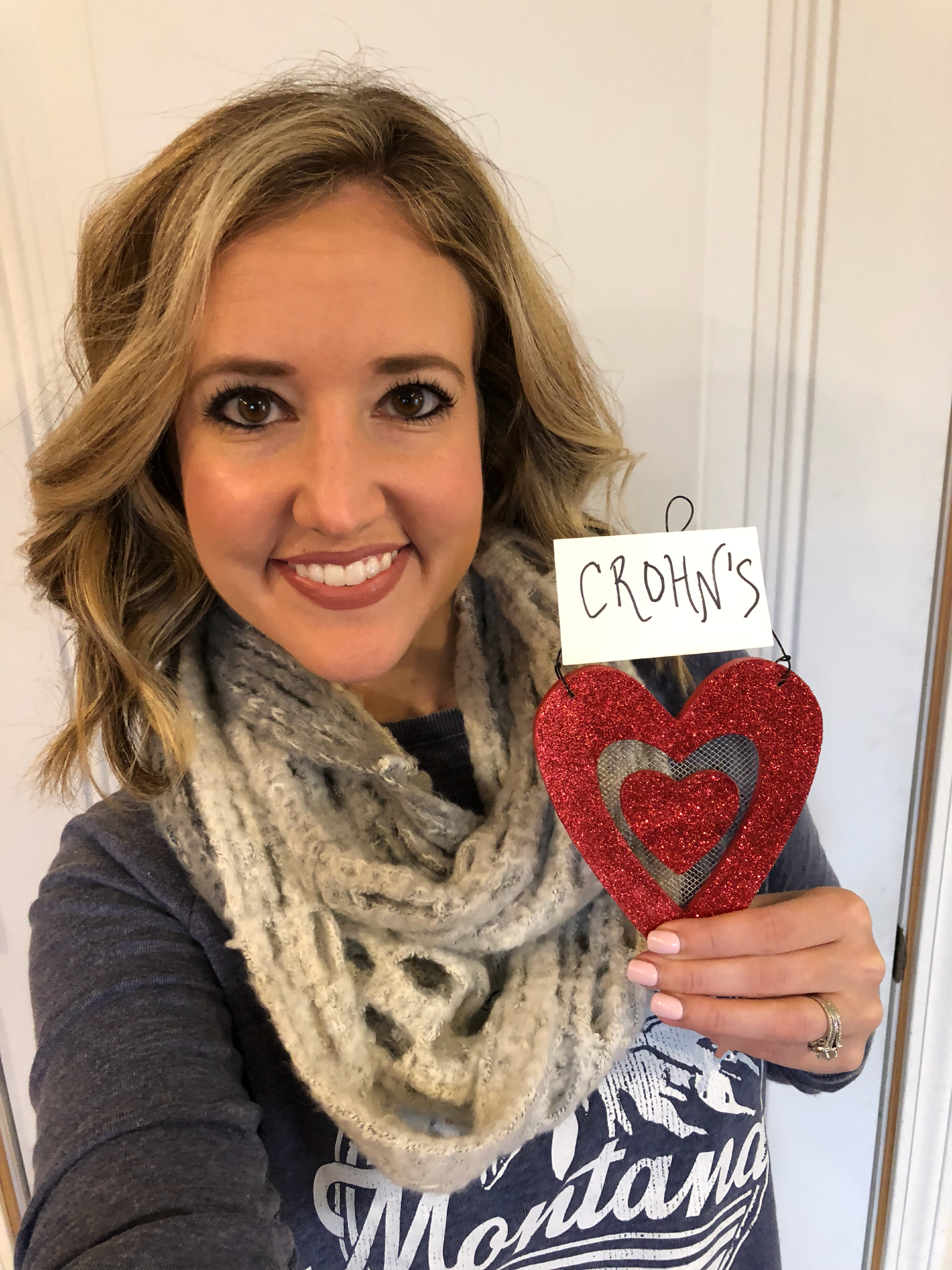 A photo of the writer holding a heart with "Crohn's" written above it.