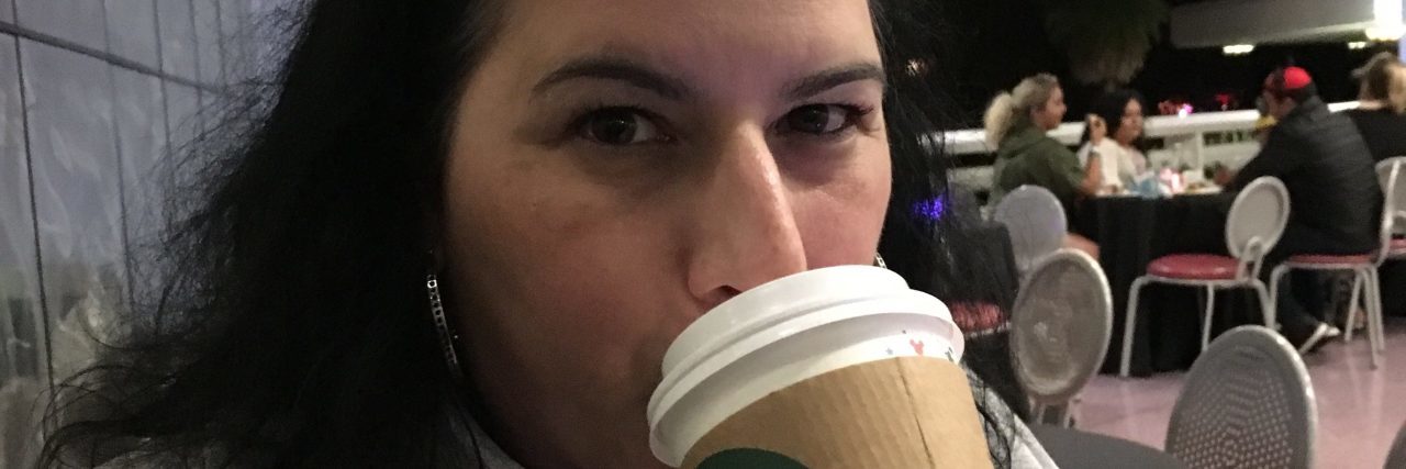 A photo of the writer wearing Mickey ears and drinking out of a Starbucks cup.