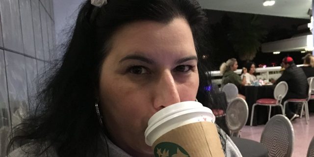 Behind the Vacation Photos of a Person With Chronic Illness A photo of the writer wearing Mickey ears and drinking out of a Starbucks cup.