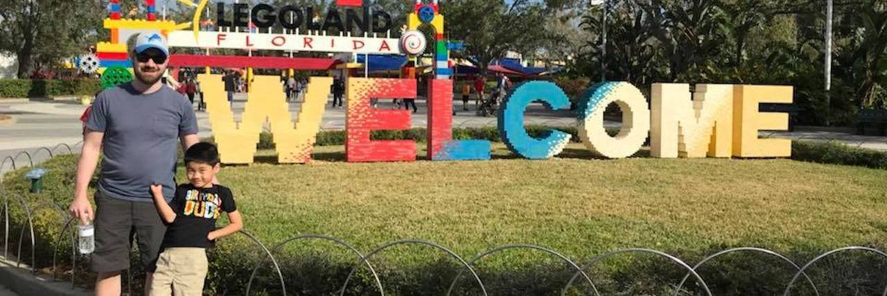 LEGOLAND Florida Prohibits Boy With Limb Differences From Rides Image of Will and his dad standing outside LEGOLAND Florida entrance.