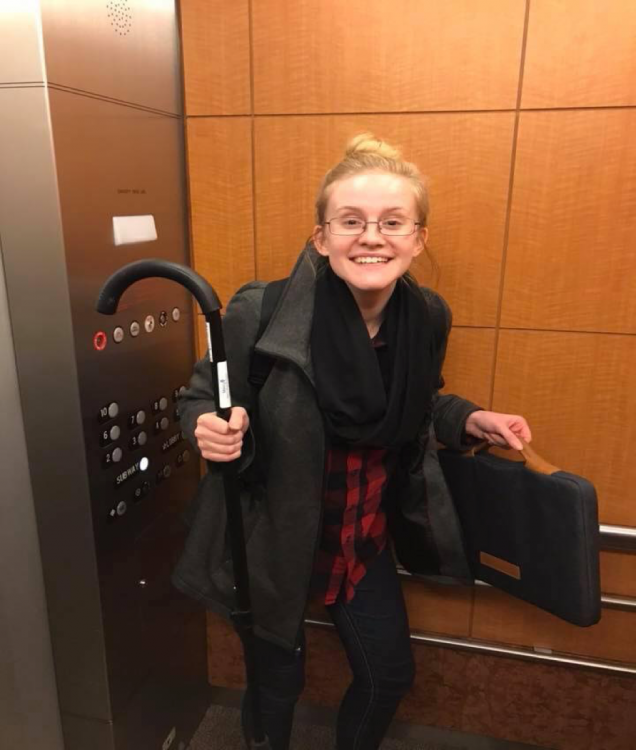 Melany holding an umbrella and standing in an elevator