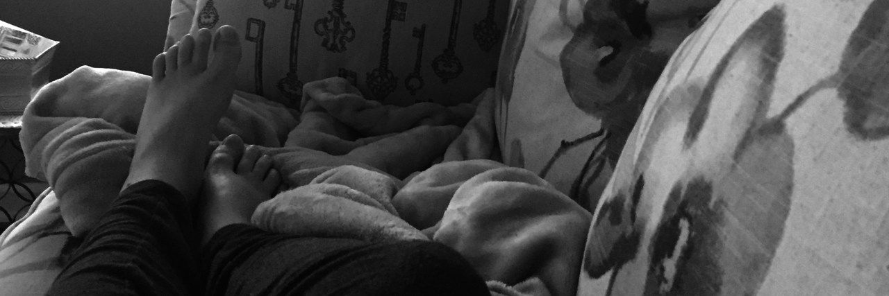 Being Medically Homebound Is Not a Vacation black and white photo of a woman's legs as she lies on her couch