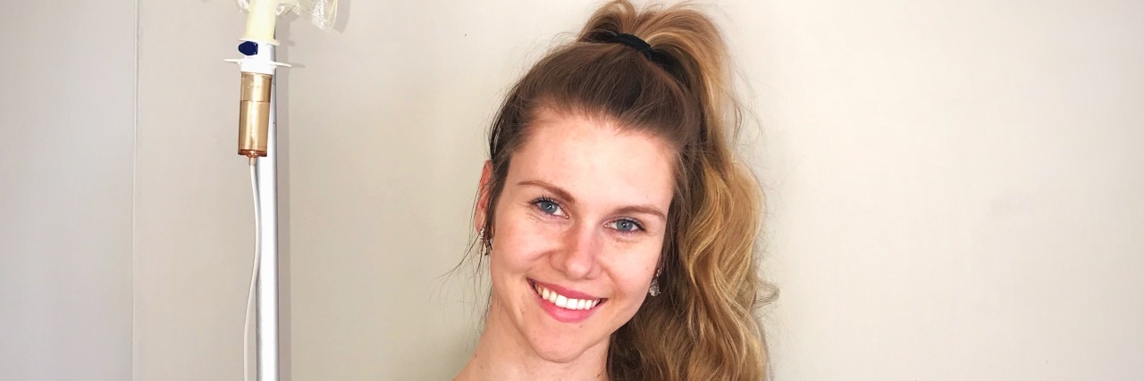 A Thank You Letter to My Rare Diseases on Rare Disease Day the author smiling with her IV pole