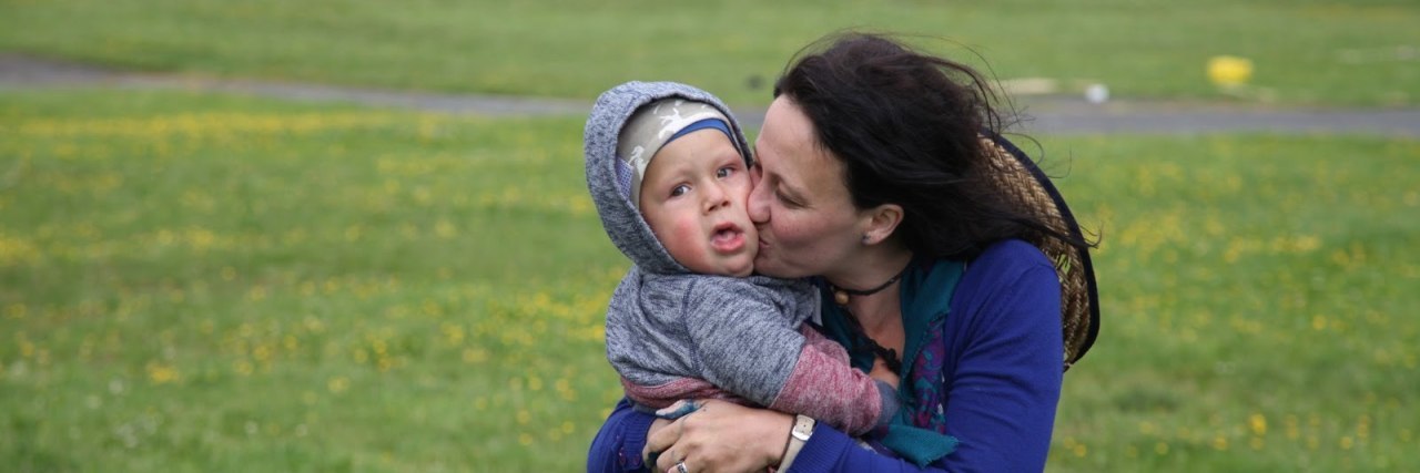 My Child With a Disability Has Made Me Into a Mother Lion Mother kissingson outdoors. Boy is wearing a hooded sweatshirt and the hood is over his head. He seems to be around 2 years old.