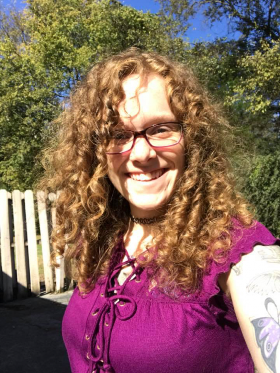 Tanya smiling with a fence and tree behind her