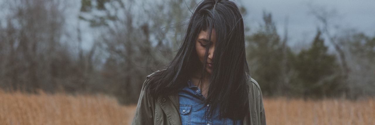 woman in field looking down with her hair in front of her face