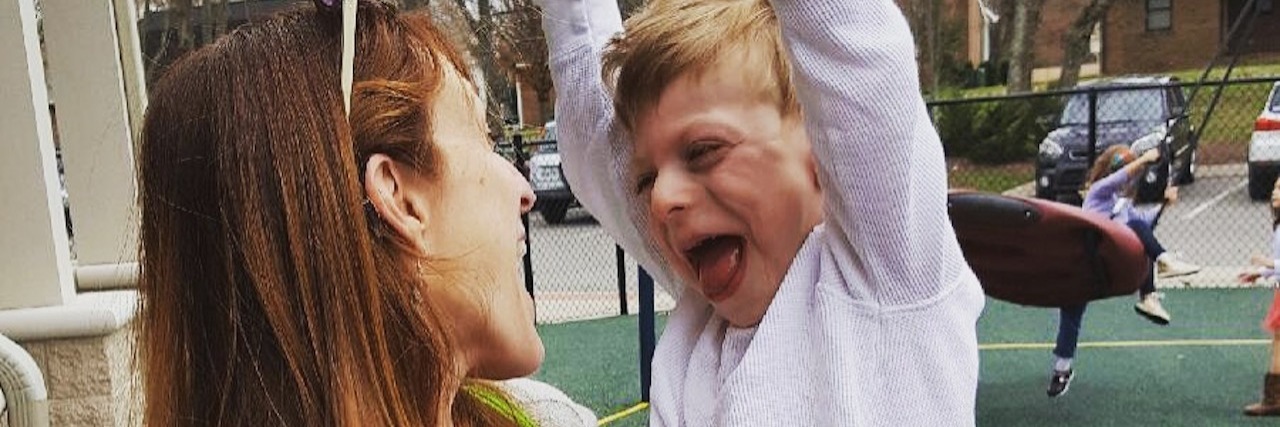 Why My Family Howls Like Wolves in Public Mother holding sun who has both arms pumping up in the air and seems to be howling