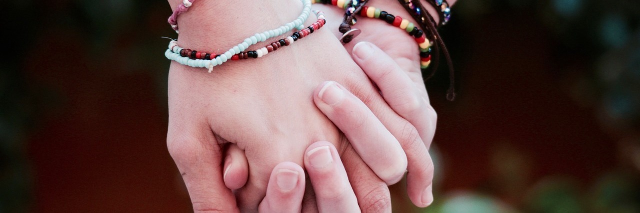 Connecting With Others Over Fibromyalgia two women wearing bracelets and holding hands