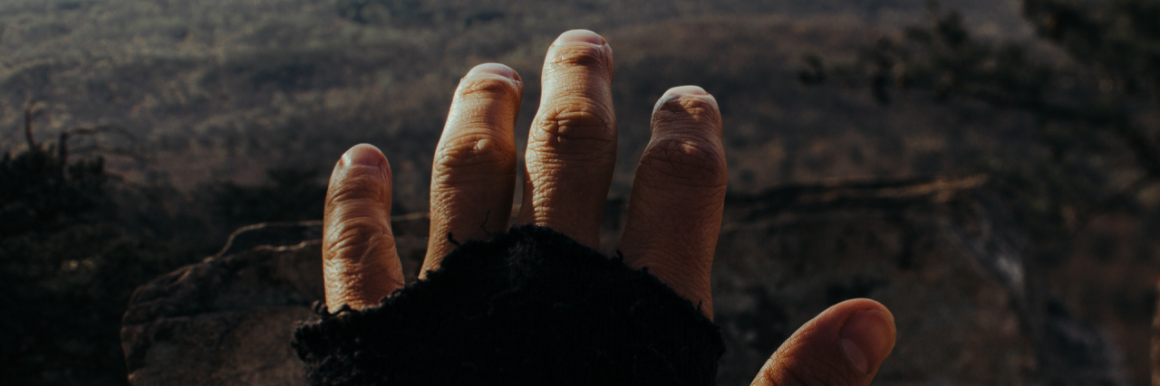 point of view shot of hand outstretched to barren landscape