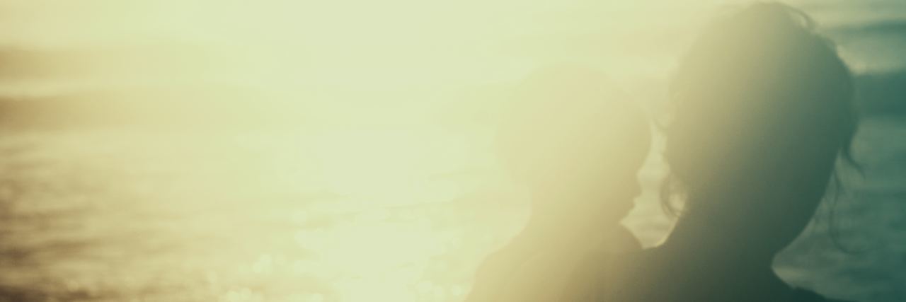 What to Do After Your Child's Rare Diagnosis With Turner Syndrome Parent holding child near the water, sunset