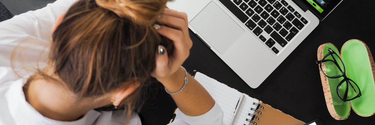 How to Survive College With Chronic Illness woman sitting at her desk working on her laptop