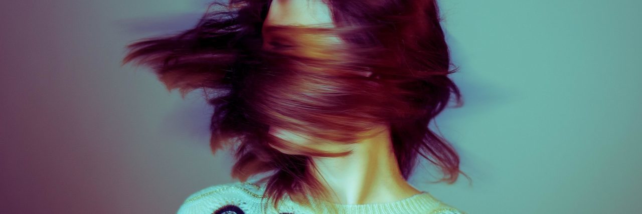 Why I Am Afraid to Speak About Dissociative Identity Disorder high contrast color blurred image of woman swinging hair covering face