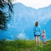 Mother and daughter standing together in clearing in front of mountains