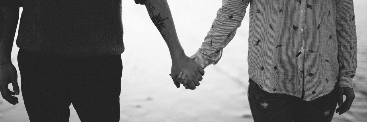 black and white photo of couple standing in lake holding hands