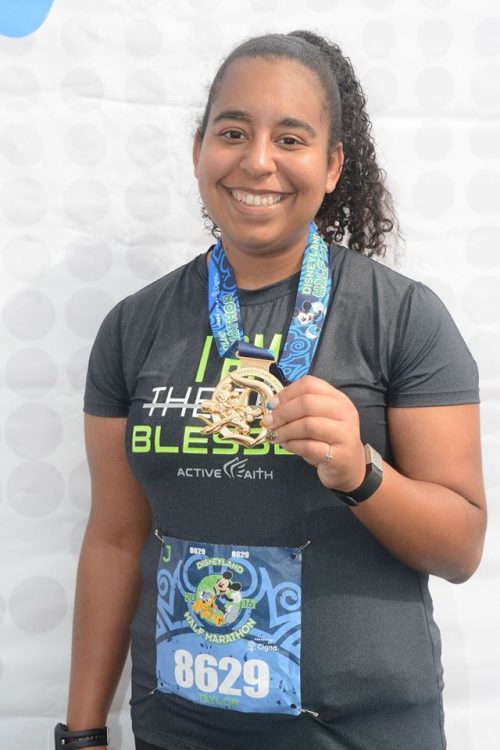 woman smiling and holding a medal around her neck after running a marathon