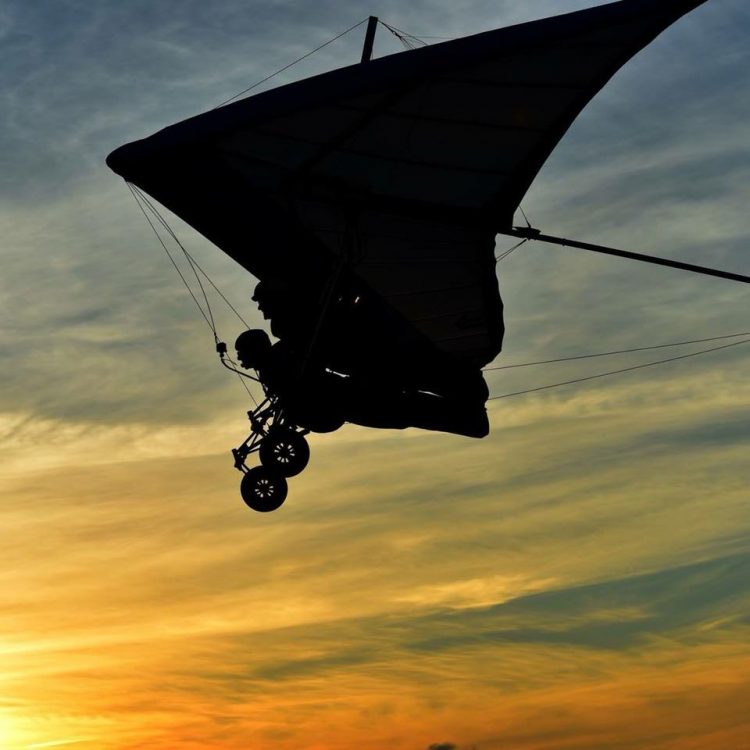 silhouette of a person flying against the sunset