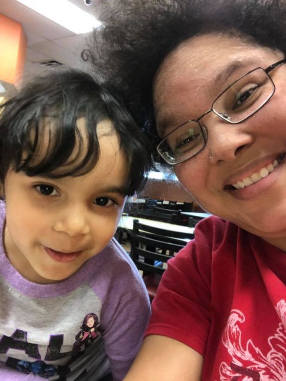 woman wearing glasses and a red shirt taking a selfie with ehr young daughter